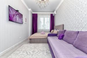 a living room with a purple couch and a bed at Лавандовые апартаменты in Astana
