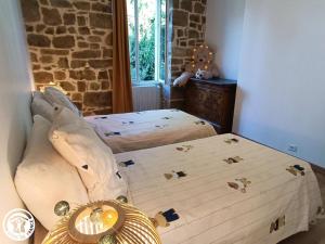 a bedroom with two beds and a stone wall at La Maison de Famille in Padirac