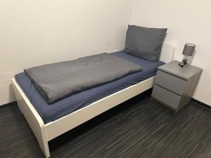 a bed with a blue blanket and a night stand at Spacious Apartment in Mörfelden-Walldorf in Mörfelden-Walldorf +2 photos