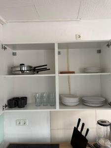a kitchen with white shelves with plates and utensils at Spacious Apartment in Mörfelden-Walldorf in Mörfelden-Walldorf