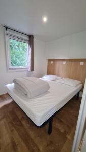 a large white bed in a room with a window at Camping du Riuferrer in Arles-sur-Tech