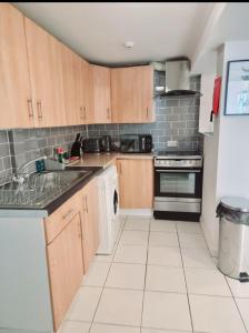 a kitchen with wooden cabinets and a stove top oven at Kent 1 bedroom apartment 2 mins walk to Gravesend Station & Town Centre in Gravesend