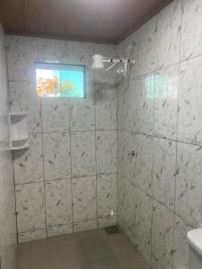 un bagno con pareti bianche piastrellate e una finestra di Chalé cabana de ferro a Alto Paraíso de Goiás