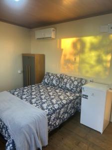 una camera con letto e piccolo frigorifero di Chalé cabana de ferro a Alto Paraíso de Goiás