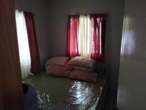 ein kleines Zimmer mit einem Bett und roten Vorhängen in der Unterkunft SMB place in Padada