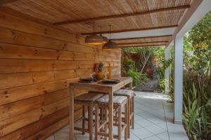 a patio with a wooden wall and a table with stools at Beach apartment, Ti Clé de Lo in Pointe-Noire