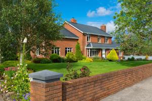 a house with a brick fence in front of a yard at Rosdarrig Bed & Breakfast in Boyle