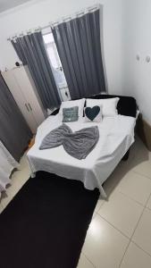 a bedroom with a white bed with two pillows at Quarto Prime até 4 pessoas familia, piscina, Pousada Lua Encantada Pousada Tijucas in Tijucas