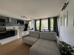 Una sala de estar con un sofá y una cocina. en Appartement Hérouville, en Hérouville-Saint-Clair