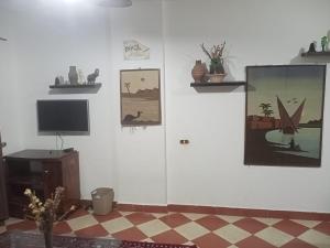 a room with white walls with paintings and a television at Riviera Apartment in Sharm El Sheikh