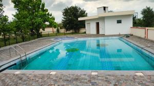 a swimming pool with blue water in front of a building at vaibhav farm house in Govindgarh Malkpur