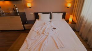un letto con lenzuola bianche e un accappatoio. di SPA Suite a Bansko