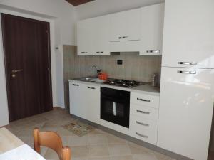 a kitchen with white cabinets and a stove top oven at Il Gelso Rosso in Comunanza