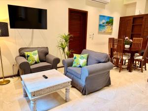 a living room with two chairs and a tv at Boutique Hotel Casa Grande, Mango Tango Suite in Santo Domingo