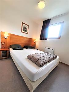 a large white bed in a room with a window at Superdévoluy T2 cosy avec terrasse sud - Vue sur Pic de Bure in Le Dévoluy
