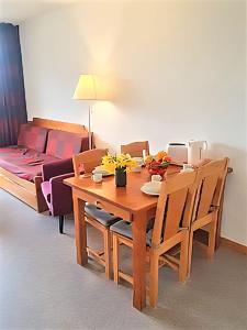 a dining room with a table and a couch at Superdévoluy T2 cosy avec terrasse sud - Vue sur Pic de Bure in Le Dévoluy +4 photos