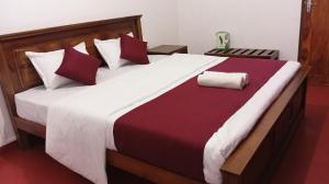 a bedroom with a large bed with red and white pillows at Ella Sunrise Villa in Ella