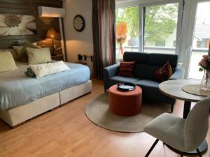 a bedroom with a bed and a couch and a table at Gezellige Ruime Villa incl Hottub Sauna en Gamesroom in Den Ham