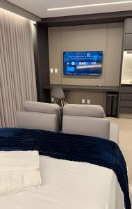 a room with chairs and a tv and a bed at Suíte Black Premium in Goiânia