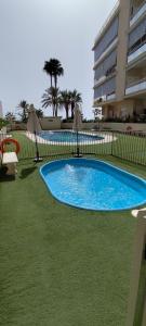 a blue swimming pool in the grass next to a building at Castell Beach - Sea front - parking - swimming pool in Castell de Ferro