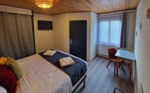 a bedroom with a bed and a desk and a window at Hôtel du Centre - Restaurant Lelex'ir in Lélex
