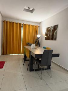 a dining room with a table and yellow curtains at CHIC cozy appart bonoumin in Abidjan