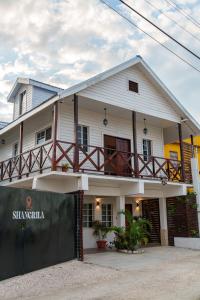 a white house with a fence in front of it at Casa De Shangrila in Belize City