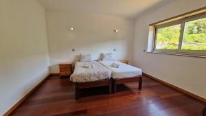 ein Schlafzimmer mit einem Bett und einem Fenster in der Unterkunft Quintela Village by Gerês Casas in Terras de Bouro