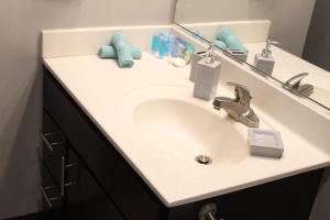 Un lavabo de baño blanco con espejo y toallas azules. en Modern Stay Near Jack Trice Stadium - Walk to ISU, en Ames 11 fotos más