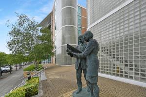 Una estatua de dos hombres de pie junto a un edificio. en Marvel House, en Milton Keynes