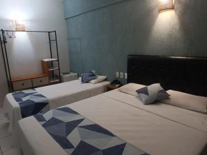 a hotel room with two beds and a mirror at Palace Hotel Três Poderes in Frutal