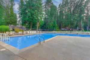 a large swimming pool with white chairs and trees at Walk to Twin Lakes All-Season Idaho Condo! in Rathdrum