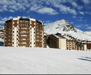 a building in the snow with a mountain in the background at Cosy Val Tho ski aux pieds in Val Thorens