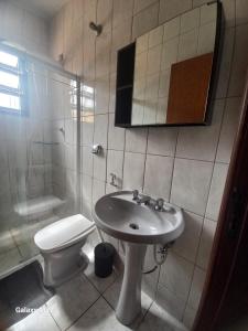 a bathroom with a sink and a toilet and a mirror at Casa de Praia in Ubatuba