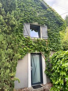 a building covered in ivy with a door and a window at Maison en lisière de forêt, montagne et vignobles in Rammersmatt