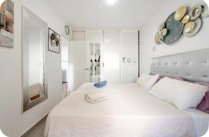 een witte slaapkamer met een groot wit bed met 2 handdoeken erop bij Exclusive ocean front apartment in Playa de las Americas +38 foto's