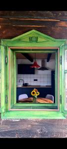 オトチャッツにあるCozy wooden house Robiniaのキッチンに花瓶に花が飾られた緑の窓