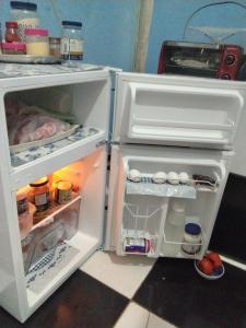 a white refrigerator with its door open and food inside at Estúdio Bambuzal no Centro in Alto Paraíso de Goiás