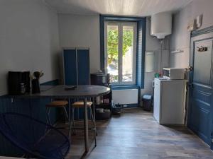 a kitchen with a table and a refrigerator at Le nid douillet Industriel in La Bourboule +4 photos