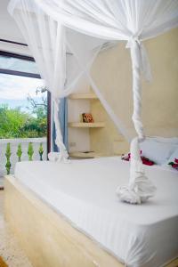 Un dormitorio con una cama blanca con dosel. en Low budget suite in Paje, en Paje