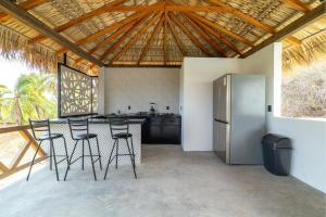 a kitchen with a bar with stools and a refrigerator at CNonoru in Puerto Escondido +44 photos
