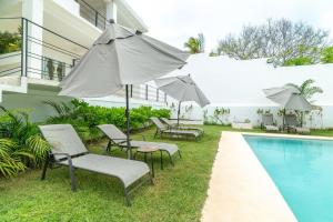 a group of chairs and umbrellas next to a pool at CNonoru in Puerto Escondido