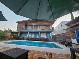 a person sitting under an umbrella next to a swimming pool at Pelican Dock Apartments in Aguada