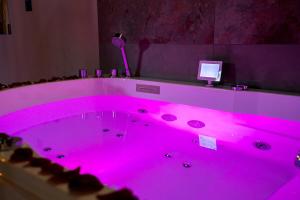 une baignoire rose vif dans une pièce avec dans l'établissement Love Room Elixir du désir, à Le Breil-sur-Mérize