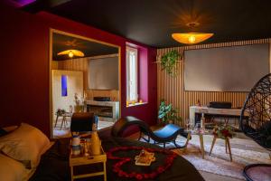 un salon avec un canapé, des chaises et un écran dans l'établissement Love Room Elixir du désir, à Le Breil-sur-Mérize