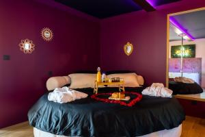 une chambre violette avec un lit avec une table dessus dans l'établissement Love Room Elixir du désir, à Le Breil-sur-Mérize