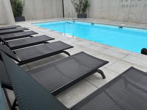 a row of lounge chairs next to a swimming pool at Apartament Virgo in Międzyzdroje