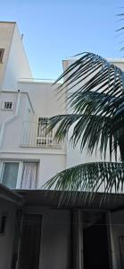 a white building with a palm tree in front of it at Bellini Holiday House in Mola di Bari