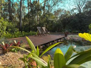 two chairs sitting on a wooden bridge over a pond at Na Mata Cabanas in Foz do Iguaçu