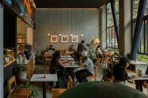 a group of people sitting at tables in a restaurant at Street Art Hotel Roma in Mexico City